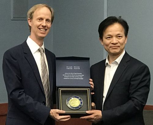 Chair Robert Harley accepts a plaque from President Zhihua Zhong